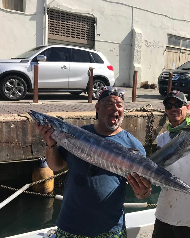 Two anglers on the dock holding up a wahoo