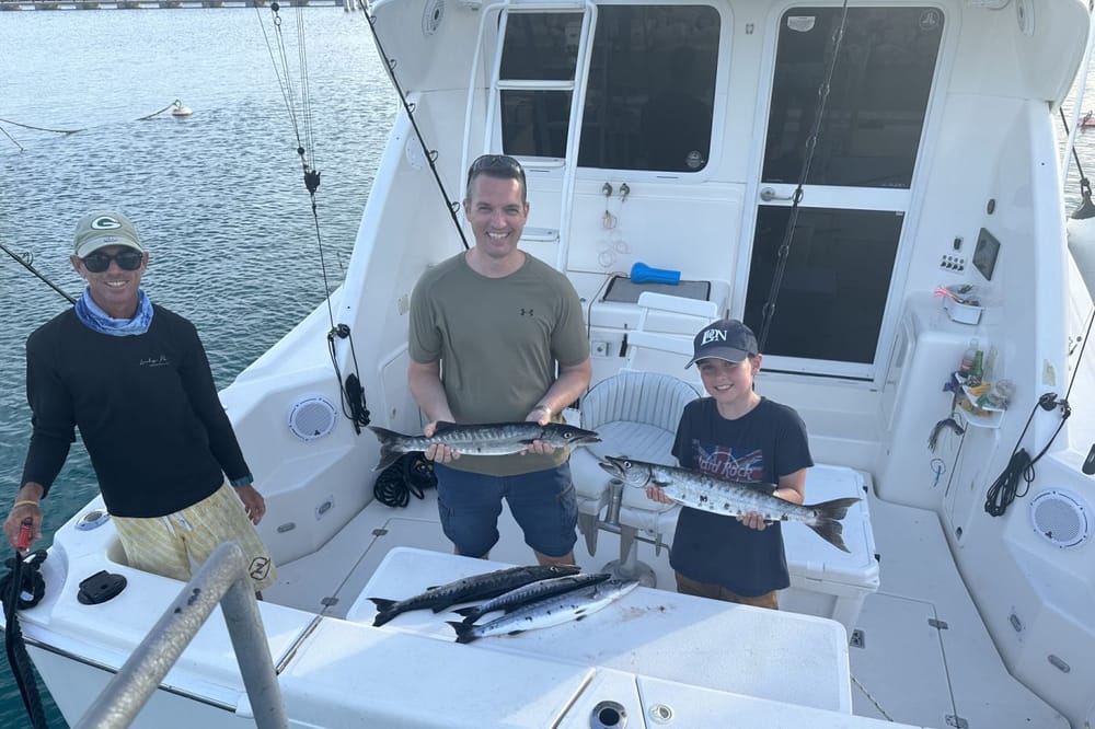 A young angler with two adults and their barracuda in the cockpit of Lucky Penny